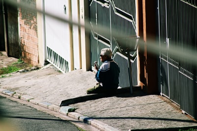 一名男子坐在大门旁的水泥地上